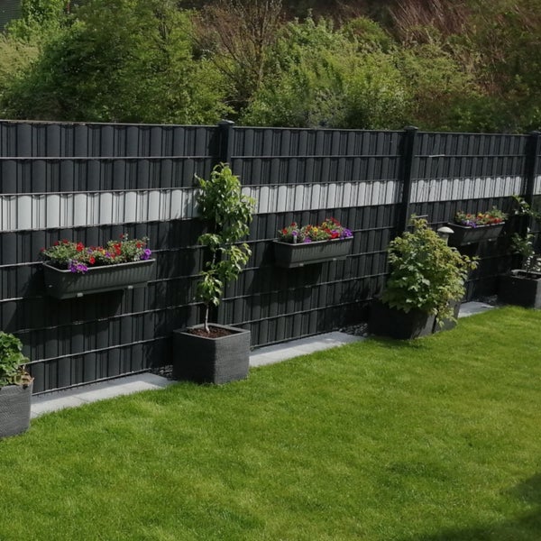 Gartenzaun mit Pflanzenkübeln und dekorativen Pflanzen