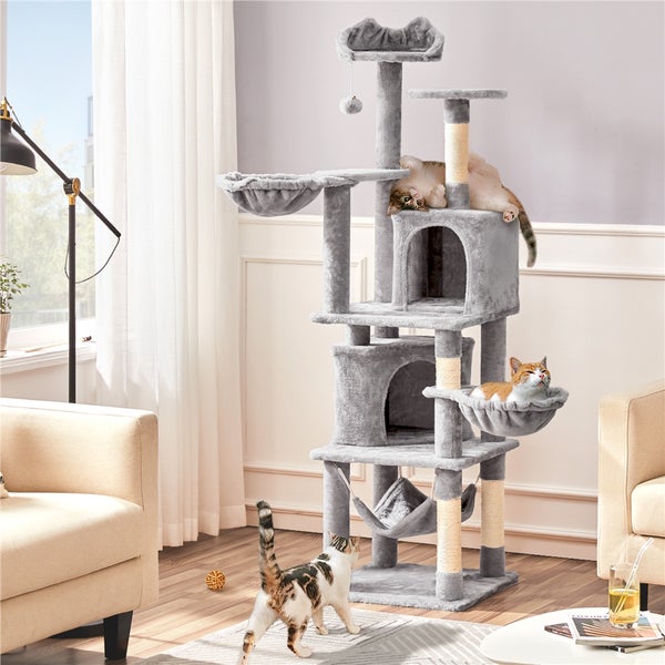 Mehrstöckiger Katzenkratzbaum mit Liegeflächen, Höhlen und Hängematte in einem Wohnzimmer mit drei Katzen