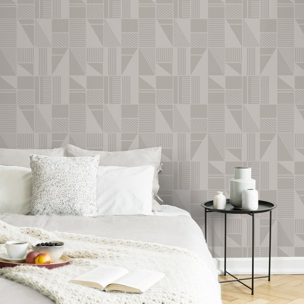 Schlafzimmer mit Bett, Beistelltisch und geometrischer Mustertapete