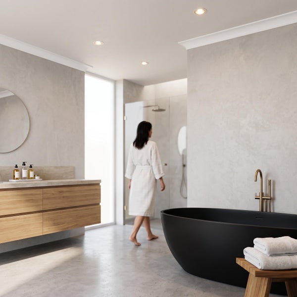 Modernes Badezimmer mit freistehender schwarzer Badewanne, hängendem Holzwaschtisch und bodenebener Glasdusche mit Person im Bademantel.