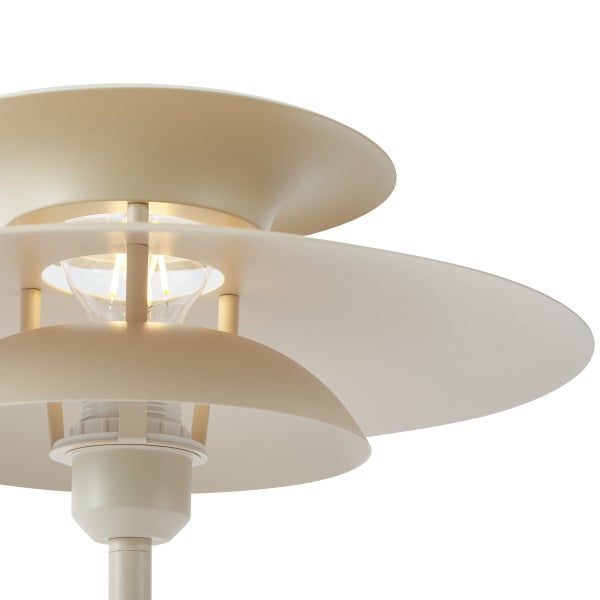 Moderne beige Tischlampe aus Metall mit einem dreistufigen kreisförmigen Schirm und sichtbarem Leuchtmittel.