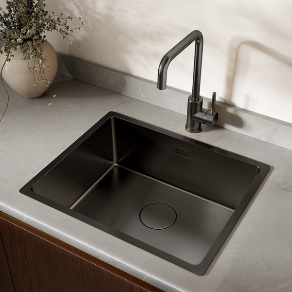 Moderne Küchenspüle mit Einhebelmischbatterie eingelassen in eine Arbeitsplatte mit Steinoptik und Blumenvase.