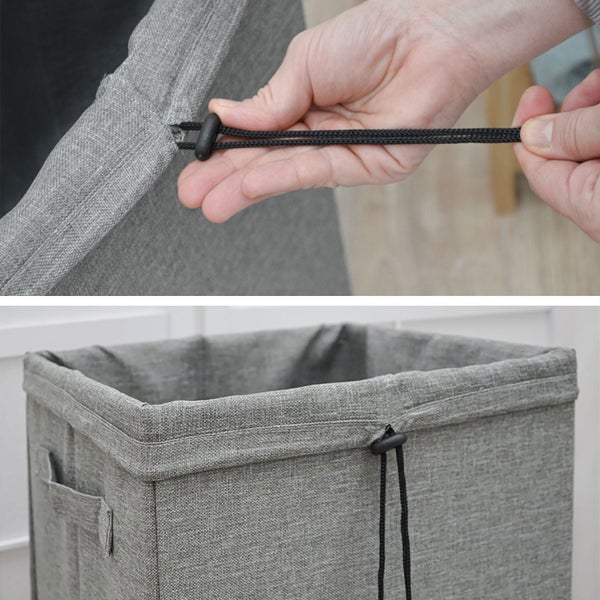 Wäschekorb aus grauem Stoff mit Kordelzug und Kordelstopper.