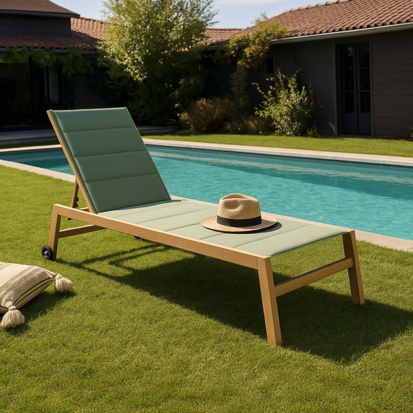 Gartenliege aus Holz mit grüner Polsterung und Rollen auf einer Rasenfläche an einem Pool.