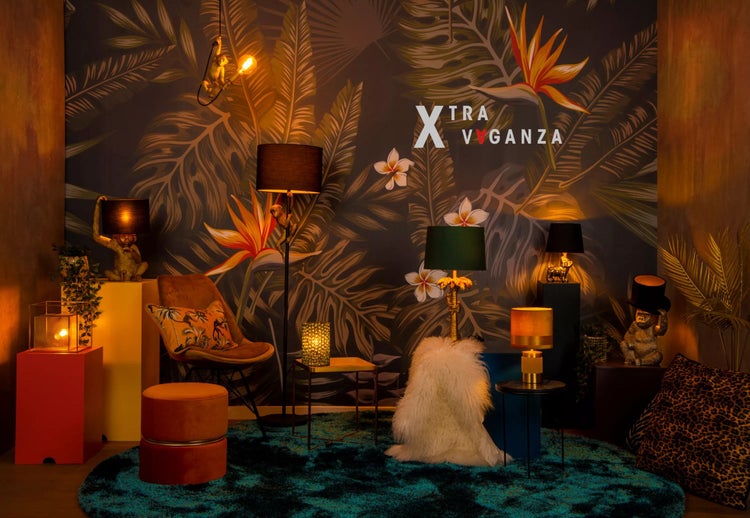 Dekoratives Wohnzimmer mit Möbeln und Lampen im Dschungelstil vor einer Dschungeltapete.