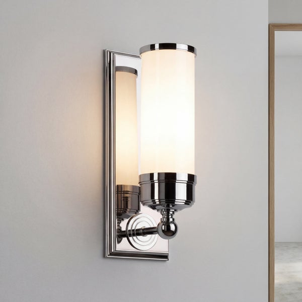 Moderne Wandleuchte aus Metall mit zylindrischem Glasschirm montiert an einer rechteckigen Wandhalterung.