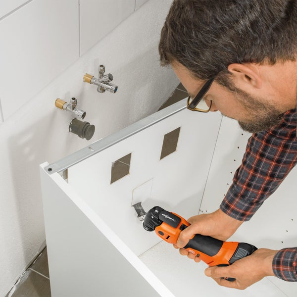 Handwerker arbeitet mit Multifunktionswerkzeug an einem Möbelstück im Badezimmer.