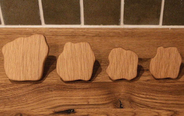 Vier Holzgriffe in unregelmäßiger Form auf einer Holzoberfläche