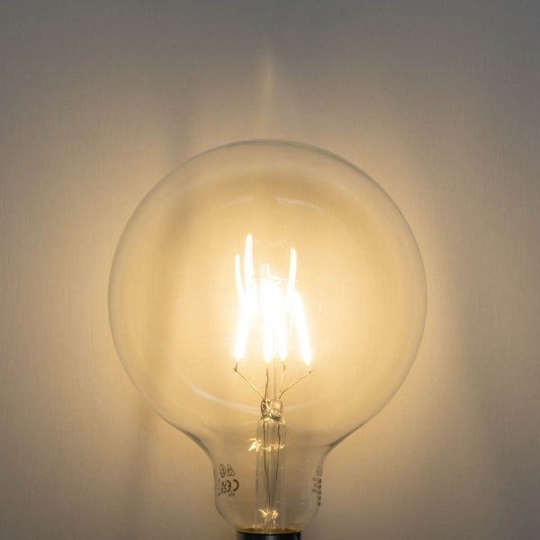 Leuchtende LED-Filament-Globelampe aus klarem Glas mit sichtbaren Glühfäden.