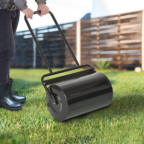 Schwarze Rasenwalze aus Metall wird von einer Person auf einem grünen Rasen im Garten verwendet.