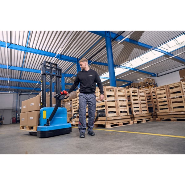 Elektrischer Hochhubwagen im Einsatz in einem geräumigen Lagerhaus beim Transport von Kartons auf einer Palette.