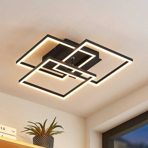 Moderne schwarze LED-Deckenleuchte mit drei überlappenden quadratischen Rahmen, montiert an einer hellen Zimmerdecke.