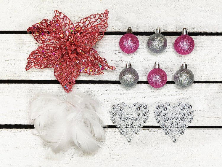Set mit Weihnachtsbaumschmuck bestehend aus einer Weihnachtsstern Blüte, kleinen Weihnachtskugeln, Herz Ornamenten und einer Federboa.