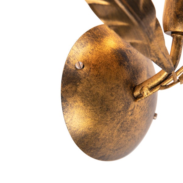 Nahaufnahme einer goldenen Wandleuchte mit Blattdesign.