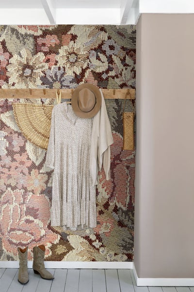 Szene mit gemusterter Tapete, Kleiderhakenleiste mit Kleid, Hut, Strickjacke, Strohhut und Strohkorb