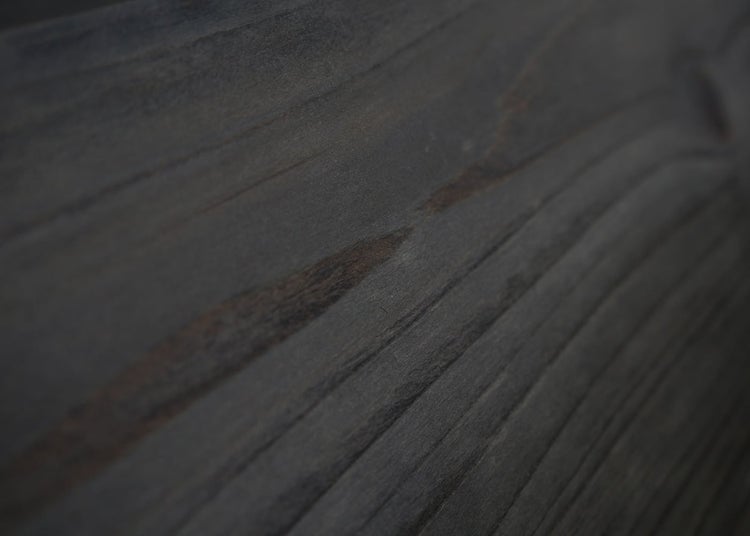 Nahaufnahme einer dunklen Holzoberfläche mit deutlicher Maserung.