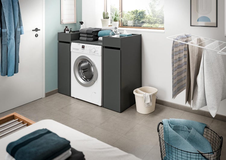 Waschmaschinenumbauschrank in modernem Design mit zwei Seitenschränken in einem organisierten Hauswirtschaftsraum.