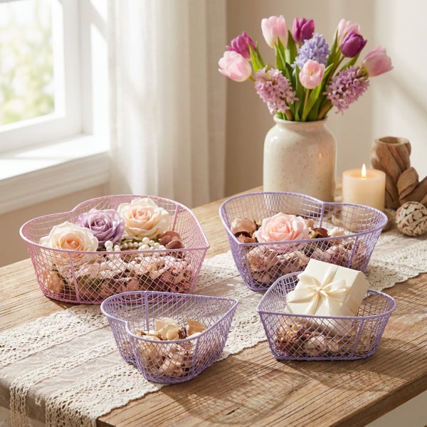 Set aus vier herzförmigen Drahtkörben als Tischdekoration auf einem Holztisch mit Blumenstrauß und Kerze