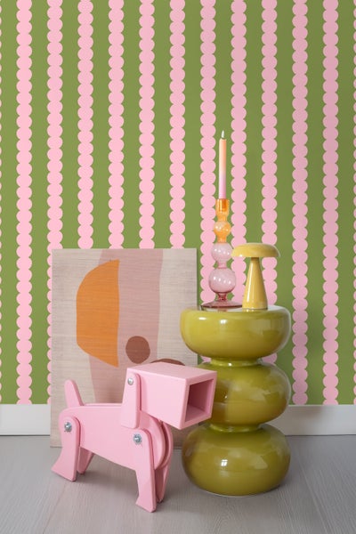 Dekorative Szene mit einer Kommode, einem Kunstwerk und einer verspielten Hundeskulptur vor einer gemusterten Tapete.