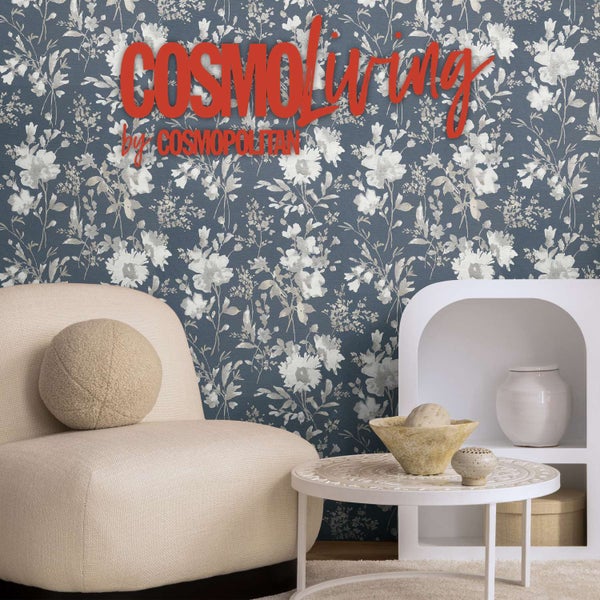 Vliestapete mit Blumenmuster vor einem modernen Sessel und Beistelltisch, Cosmopolitan Logo.