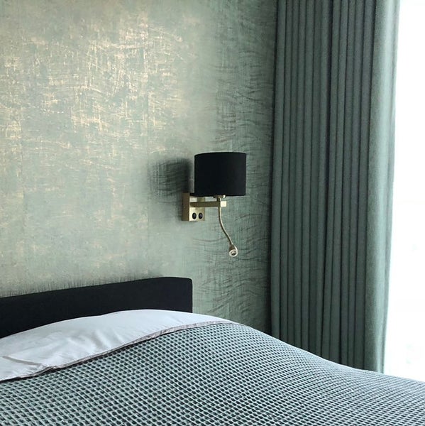 Schlafzimmer mit Bett, Wandleuchte und Vorhängen