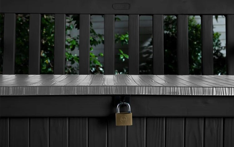 Yale Vorhängeschloss an einer dunklen Garten-Aufbewahrungsbox mit Holzmaserung.