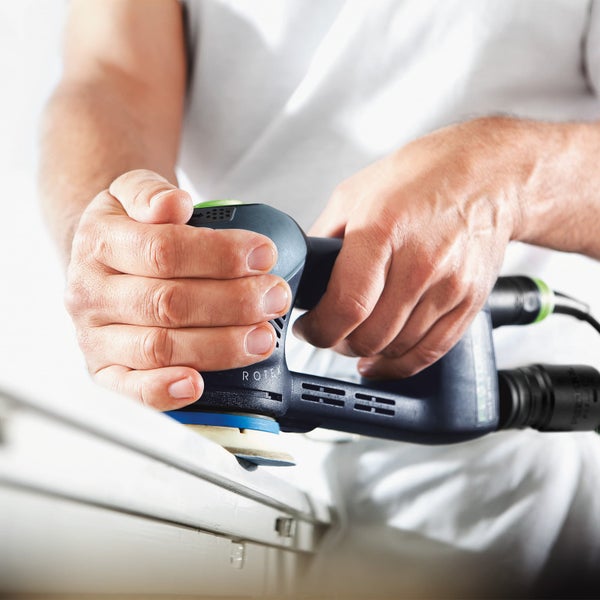 Mann schleift mit einem Exzenterschleifer eine Oberfläche