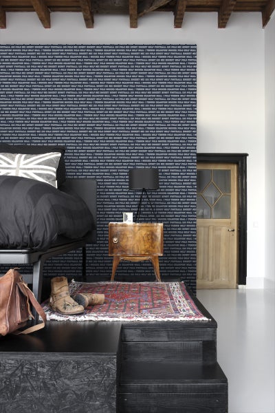 Schlafzimmer mit Bett, Nachttisch, Teppich und gemusterter Tapete