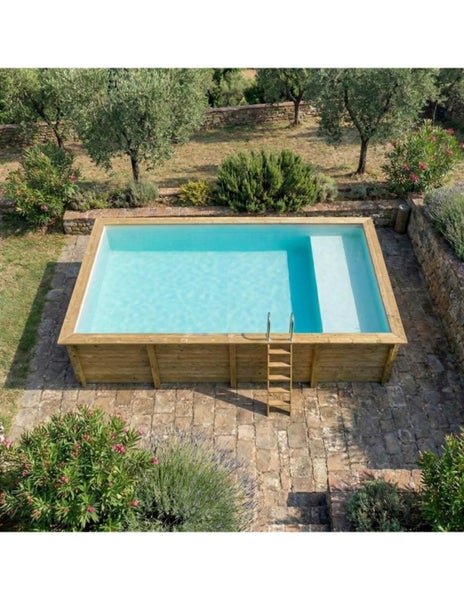 Rechteckiger Holzpool mit Leiter in einem Garten mit Steinterrasse und Vegetation.