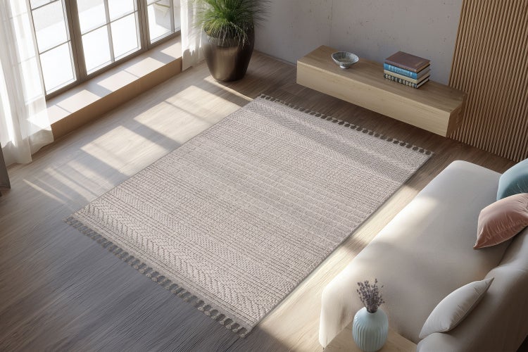 Wohnzimmer mit einem texturierten Webteppich mit Fransen, der auf einem hellen Holzboden vor einem Sofa und einem modernen Sideboard liegt.