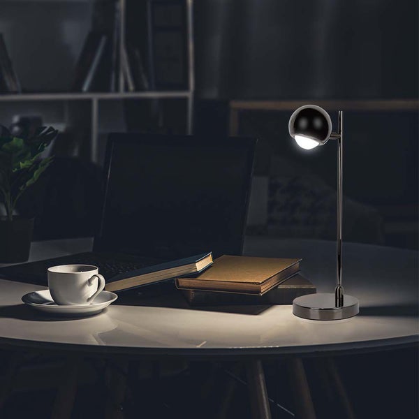 Szene mit Schreibtischlampe, Laptop, Büchern und einer Tasse auf einem Tisch