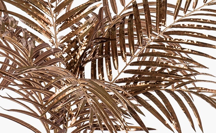 Nahaufnahme einer künstlichen Palme mit metallisch glänzenden Palmwedeln und Stamm.