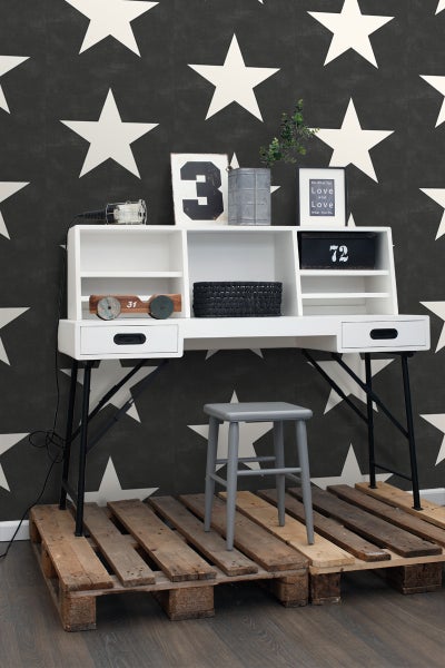 Modernes Arbeitszimmer mit Schreibtisch, Regalaufsatz und Hocker auf Holzpalette vor einer Wand mit Sternenmuster.