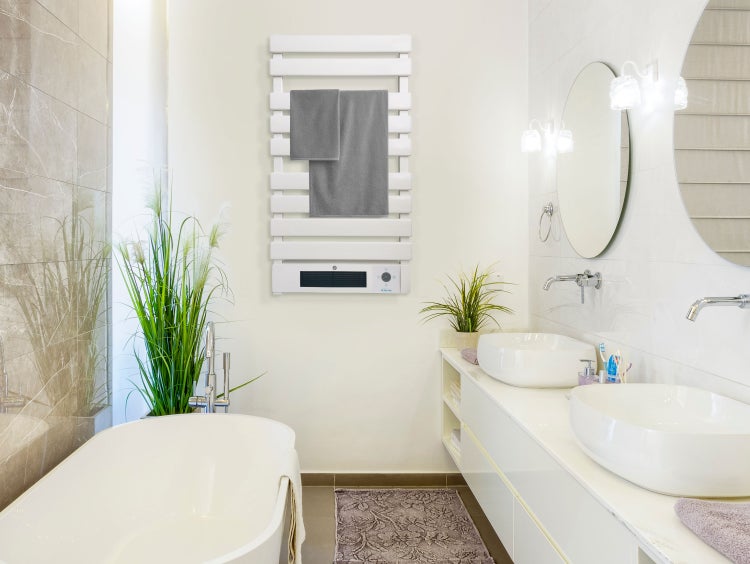 Helles Badezimmer mit Badewanne, Waschtisch mit zwei Waschbecken und beheiztem Handtuchhalter mit Handtüchern