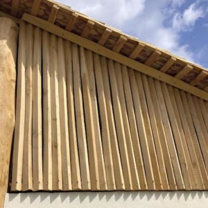 Vertikale Holzlatten als Fassadenverkleidung unter einem Dachüberstand montiert.