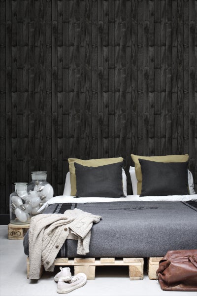 Schlafzimmer mit Holzwandtapete, Bett auf Holzpalette, Gläsern mit Glühbirnen