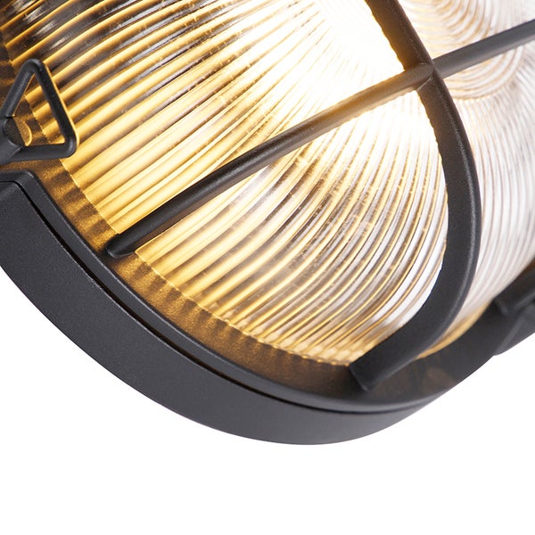 Detailansicht einer eingeschalteten Außenwandleuchte mit schwarzem Metallgitter und geriffeltem Glas.