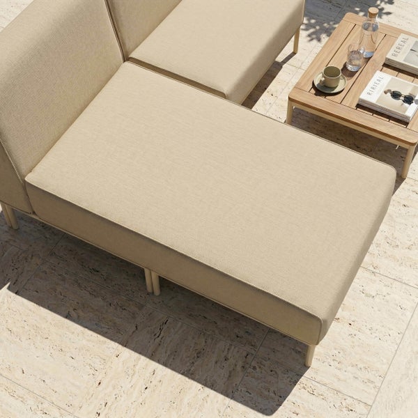 Modulares Garten-Loungesofa mit Stoffpolstern und einem Beistelltisch aus Holz auf einer Steinterrasse.