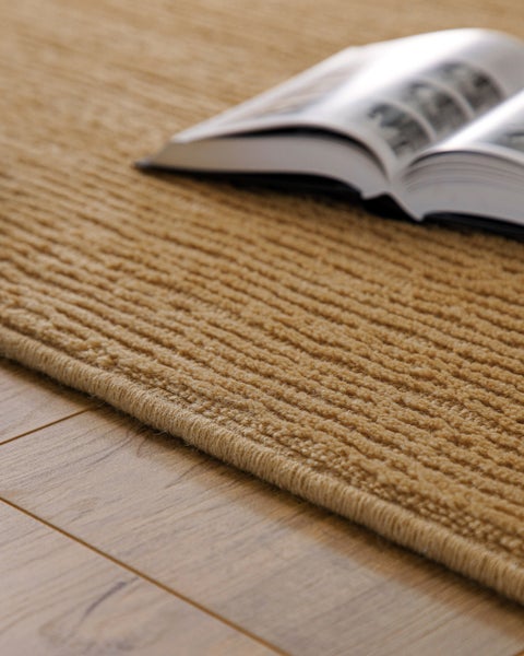 Strukturierter Teppich mit Rippenmuster auf einem Holzfußboden.