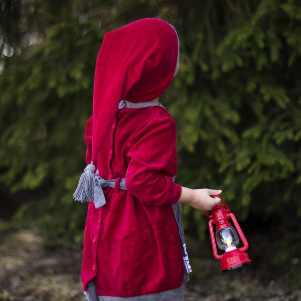 Kind mit rotem Gewand und roter Laterne im Aussenbereich