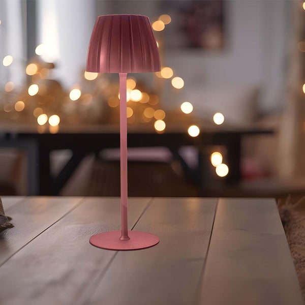 Dekorative Tischleuchte auf einem Holztisch mit Lichtpunkten im Hintergrund.