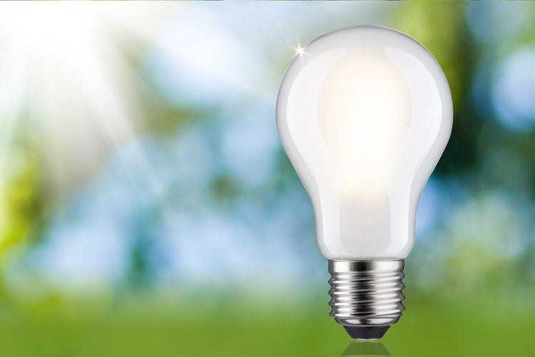 Matte LED-Lampe in klassischer Kolbenform mit E27-Sockel, hell leuchtend vor einem unscharfen Naturhintergrund.