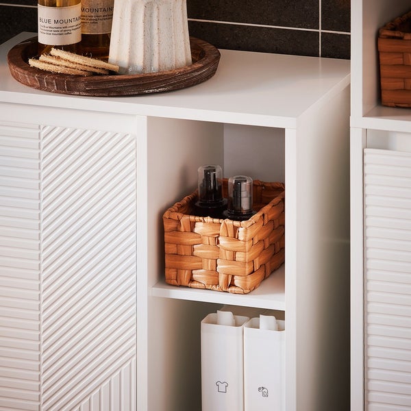 Detailaufnahme eines weißen Badezimmerschranks mit Ablagefächern und verschiedenen Badutensilien