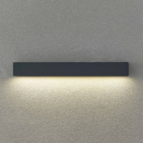 Moderne Wandleuchte in länglicher Balkenform aus schwarzem Metall mit nach unten gerichtetem Licht auf einer strukturierten Wand.
