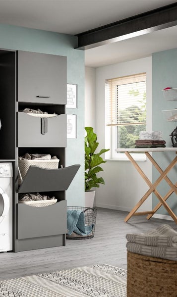Moderner Hauswirtschaftsraum mit grauem Hochschrank für Wäschekörbe, Waschmaschine und Holz-Bügelbrett vor hellem Fenster.