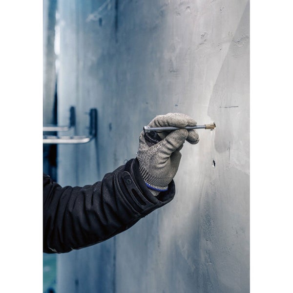 Eine Person, die eine Schraube in eine Betonwand mit einem Schraubendreher schraubt