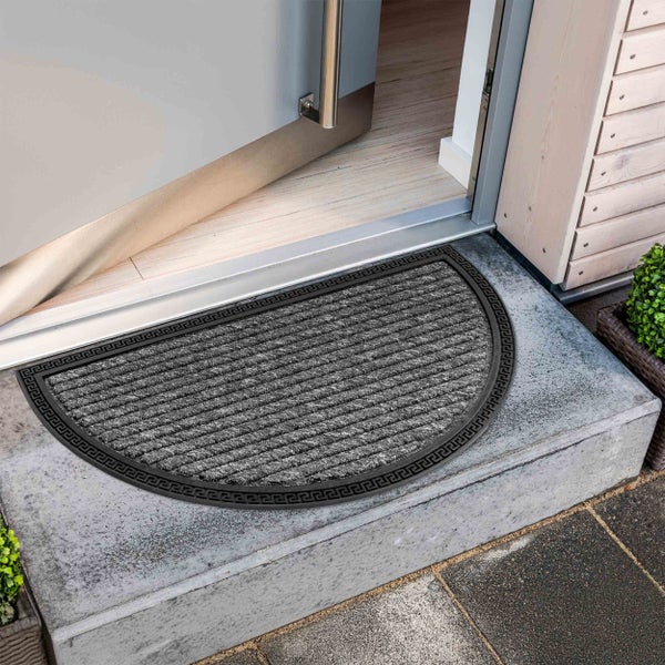 Halbrunde Fußmatte vor einer geöffneten Tür auf einer Treppenstufe