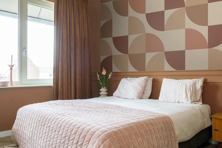 Schlafzimmer mit Bett, Vorhängen und gemusterter Tapete