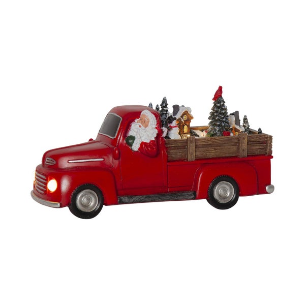 Dekorativer roter Truck mit Weihnachtsmann, Tannenbaum und Haus als Weihnachtsdekoration.