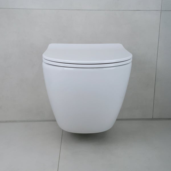 Wandtoilette aus weißer Keramik, montiert an einer Wand mit Fliesen.